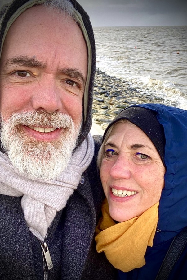 Manuela und Stefan, dick eingemummelt am Deich vor rauer See.